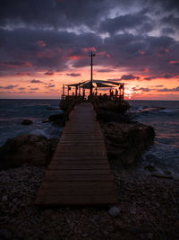 Pier over sea against sky during sunset