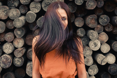 Woman with long hair standing against logs