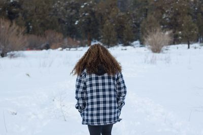 Rear view of woman walking on snow field