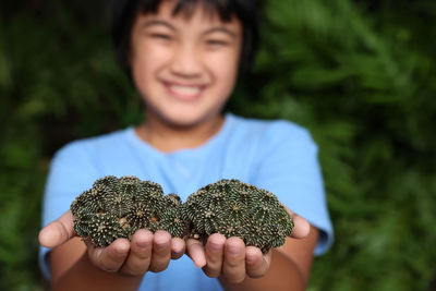 Portrait of smiling boy holding plant