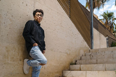 Confident transgender person posing standing outdoors on a walkway.