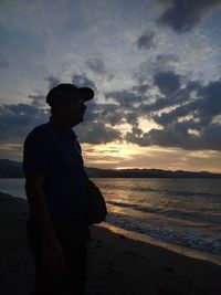 Man standing on beach against sky during sunset