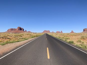 Empty road against clear blue sky