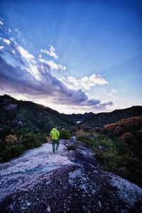 Rear view of man walking on mountain against sky