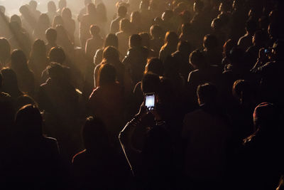 High angle view of woman photographing amidst crowd in music concert