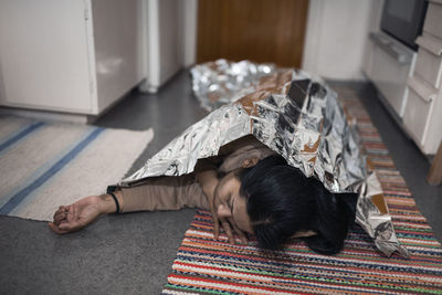 Unconscious woman in medical shock lying under emergency blanket
