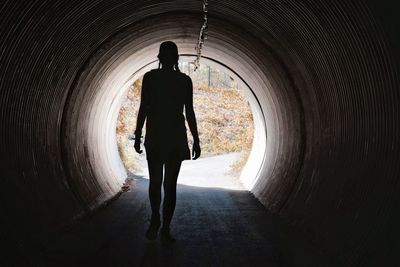 Full length rear view of silhouette man walking in corridor