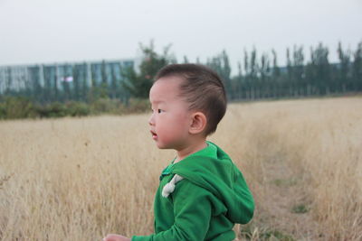 Side view of cute baby boy standing on grassy field