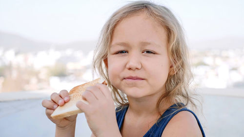 Portrait of cute girl eating bread outdoors