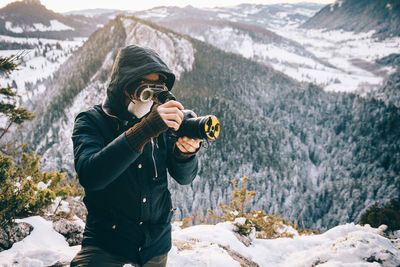 Woman photographing on snow covered mountain