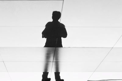 Rear view of man standing against clear sky