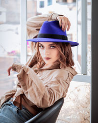 Rear view of woman wearing hat standing by window