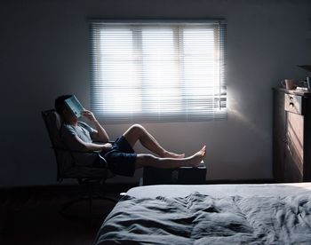 Man resting while reading book in bedroom at home