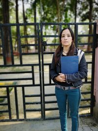 Portrait of woman standing against closed gate