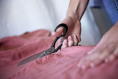 Cropped hand of man cutting textiles