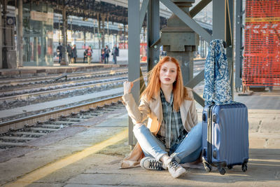 Portrait of woman sitting at railroad station platform