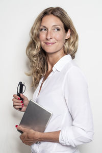 Smiling businesswoman holding tablet and glasses