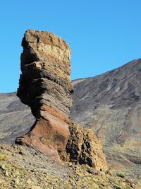 Rock formation on volcanic landscape against sky