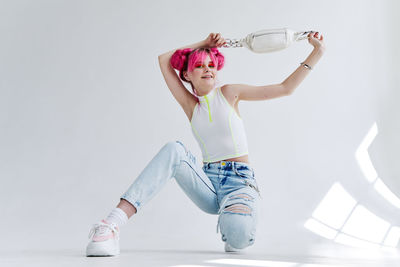 Rear view of young woman exercising against white background