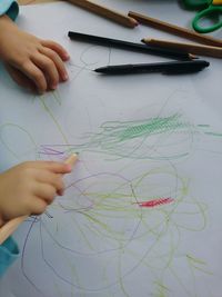 Cropped hands of child drawing on cardboard