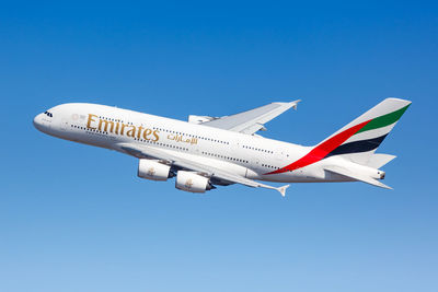 Low angle view of airplane flying against clear blue sky