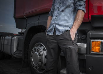 Low section of man standing by car