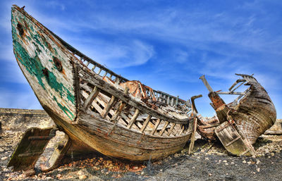 Close-up of abandoned boat against sky