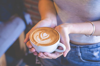 Midsection of woman holding coffee cup