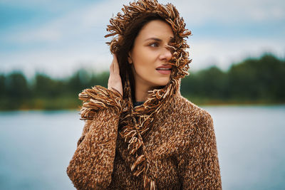 Beautiful young woman looking away standing by lake