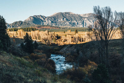 Scenic view of river by mountains against clear sky