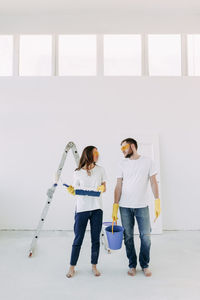 Full length of woman standing against wall at home