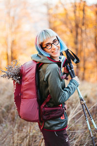 Side view of young woman with backpack walking on field