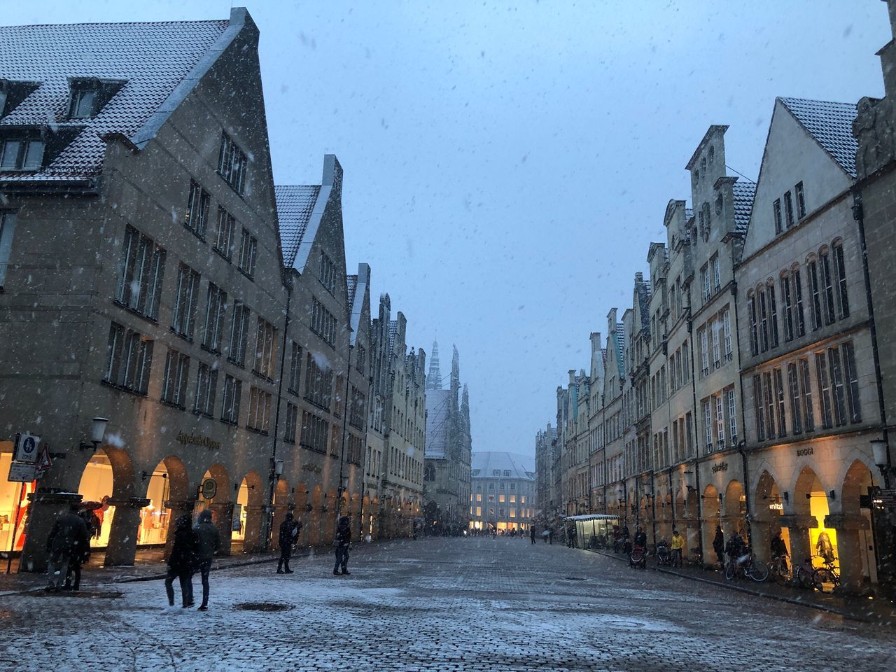 PEOPLE WALKING ON STREET AMIDST BUILDINGS DURING WINTER