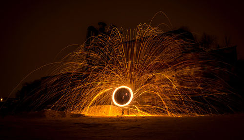 Firework display at beach against sky at night