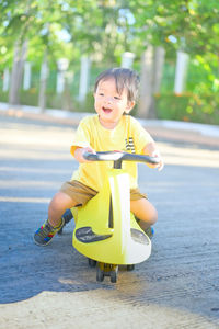 Portrait of cute boy sitting on yellow playing