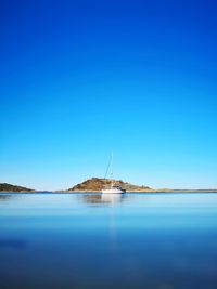 Sailboats in sea against clear blue sky