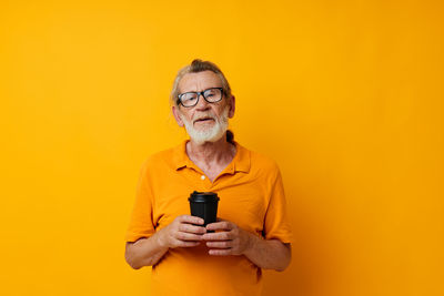 Young woman using mobile phone against yellow background