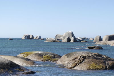 Rocks in sea against clear sky