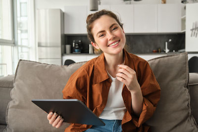 Young woman using digital tablet while sitting at home