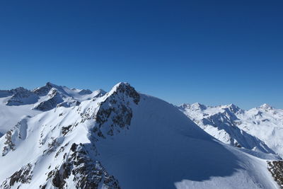 Scenic view of snowcapped mountains against clear blue sky