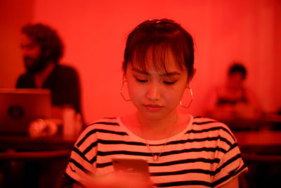 Woman using smart phone while sitting in red room