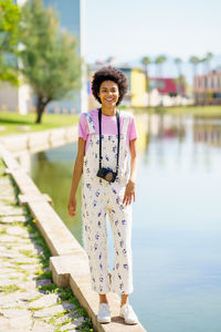 Portrait of smiling young woman standing against lake