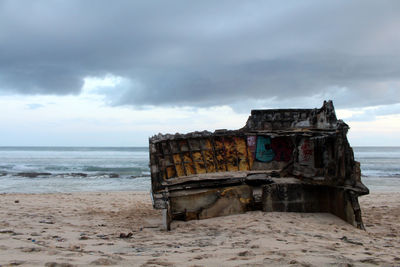 Abandoned chair on beach against sky