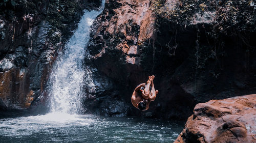 Man surfing on rock in sea