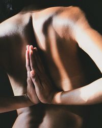 Midsection of shirtless woman doing yoga
