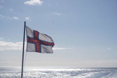 Flag by sea against sky