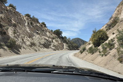 Road amidst mountains seen through car windshield