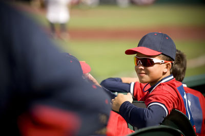 Boy wearing sunglasses and smirking in baseball uniform