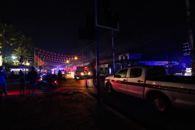 Cars on city street by buildings at night