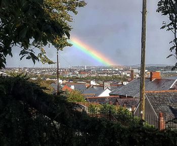 Rainbow over cityscape against sky